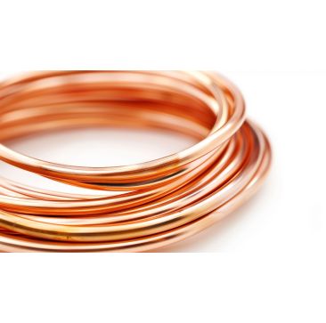 A close-up side view of a tightly coiled copper tube, highlighting its smooth, shiny reddish-brown surface. The coil is neatly wound in a circular shape against a white background, emphasising the quality and uniformity of the tubing for refrigeration and