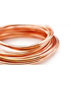 A close-up side view of a tightly coiled copper tube, highlighting its smooth, shiny reddish-brown surface. The coil is neatly wound in a circular shape against a white background, emphasising the quality and uniformity of the tubing for refrigeration and