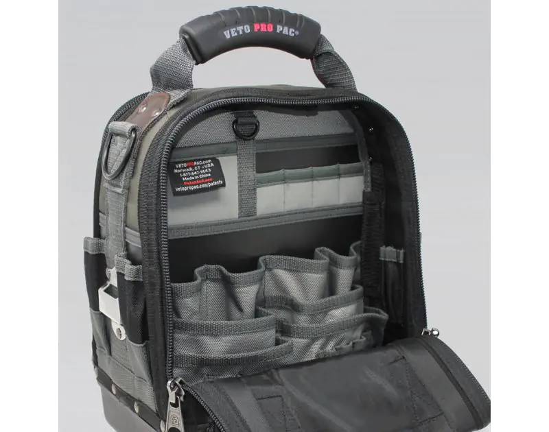 Close-up interior view of an open Veto Pro Pac Tech Pac tool backpack, displaying its organised storage with multiple grey pockets and slots for tools. The bag features a sturdy handle, durable zippers, and a label with Veto Pro Pac branding, designed for