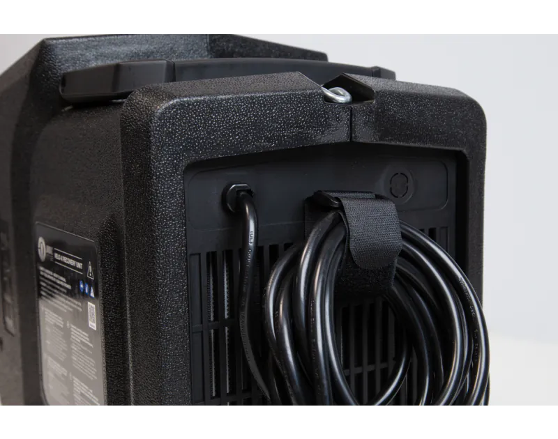 This is a rear view of a JAVAC Edge vacuum pump, showing its black textured casing. The back panel includes a label with the text "VACUUM RECOVERY UNIT" and various warning symbols, including a QR code. Several black hoses are neatly coiled and secured wi