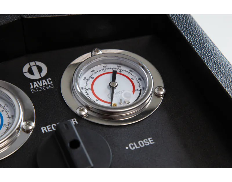A close-up view of a JAVAC Edge vacuum pump control panel. The panel features a circular vacuum gauge with a needle pointing to approximately 50 microns, labelled "JAVAC Edge" in the centre. The gauge has a red outer ring with micron measurements ranging 