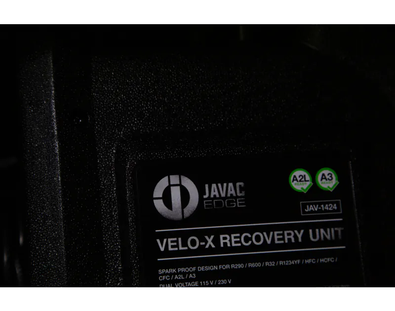 A close-up view of a black JAVAC Edge Velo-X Recovery Unit, showing a label with the following details: "JAVAC Edge Velo-X Recovery Unit, Spark Proof Design for R290 / R600 / R32 / R1234YF / HCFC / HFC / CFC / A2L / A3, Dual Voltage 115 V / 230 V." The la