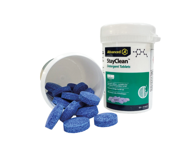 A white plastic bottle labelled "Advanced A StayClean Detergent Tablets" with a blue cap contains small, round blue tablets for air conditioning drain maintenance. Several blue tablets spill out onto a white surface, and green accents on the label highlig